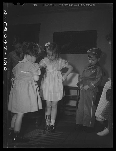 Buffalo, New York. Mrs. Grimm, a twenty-six year old widow, is a crane operator in a war plant. Her two youngest children live in a foster home during the week. Their foster mother, Mrs. Hehr, gave a birthday party for Mona, two, invited Mrs. Grimm and the children. Here they are playing a peanut ga