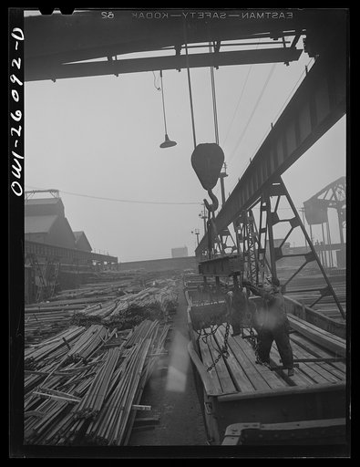 Untitled photo, possibly related to: Buffalo, New York. Two "hookers" load a crane from a gondola car in the Republic Steel yard