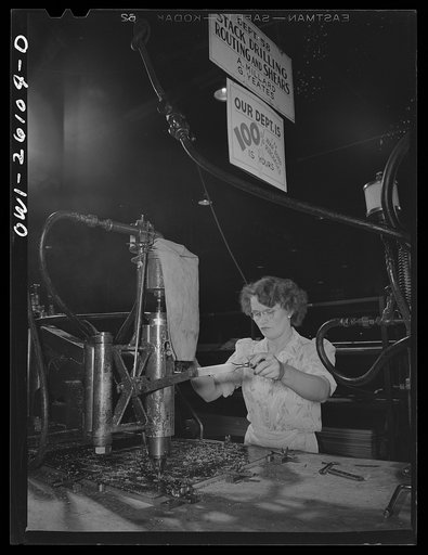 Bell Aircraft Corporation, Niagara Falls, New York. Stack drilling from a template. The sign in the background shows that the department has a 100% war bond purchase record
