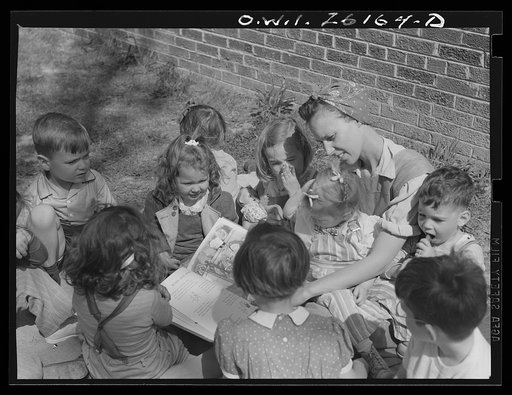 Washington, D.C. A day nursery for pre-school children of mothers engaged in war work, operated under the supervision of the District of Columbia Health Department by Mrs. Leroy Bonbrest at her home at 1144 Branch Avenue, S.E. Mrs. Bonbrest and the children out in the yard looking at a picture book