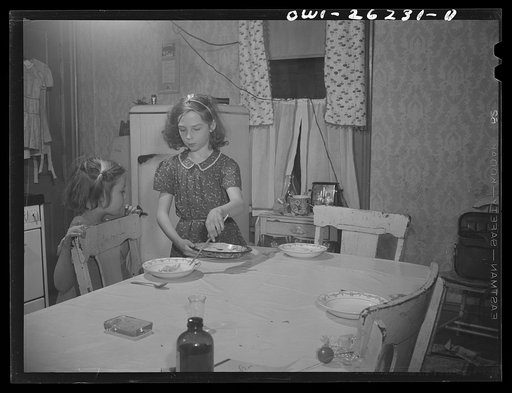 Buffalo, New York. Beverly Ann Grimm, eleven, serving an omelette for Saturday lunch for her sisters and herself, while Pasty looks on. Their mother, a twenty-six year old widow, is a crane operator at Pratt and Letchworth