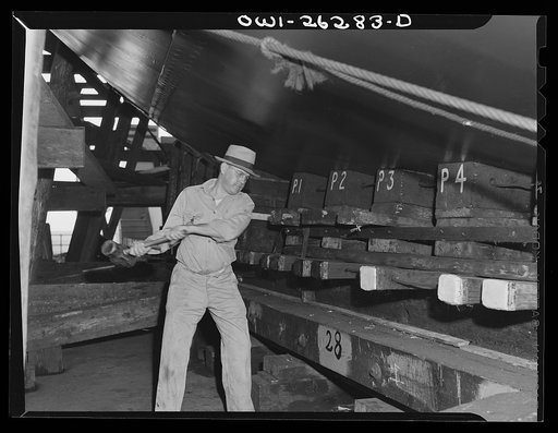Bethlehem-Fairfield shipyards, Baltimore, Maryland. Preparations for launching a ship. Driving wedges to lift the ship from the keel blocks