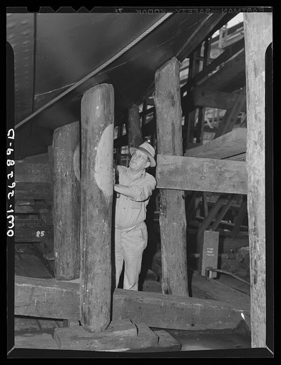 Bethlehem-Fairfield shipyards, Baltimore, Maryland. Preparations for launching a ship. Removing poppins