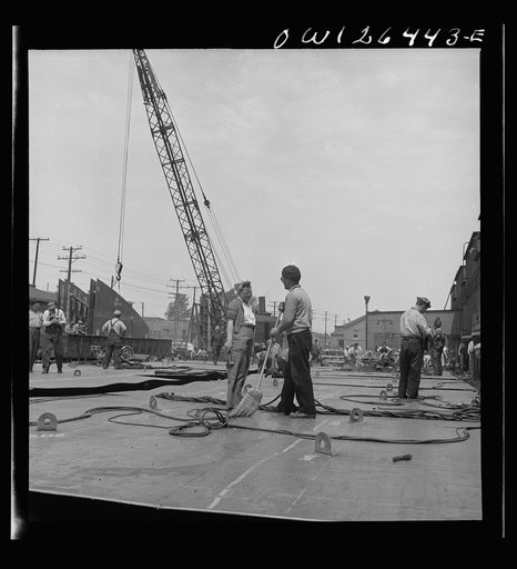 Untitled photo, possibly related to: Bethlehem-Fairfield shipyards, Baltimore, Maryland. Transferring a steel section from the fabricating table to a railroad car