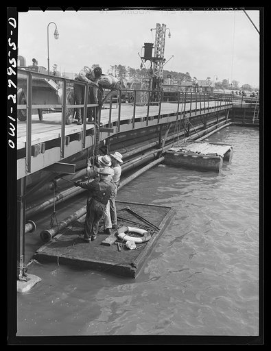 Untitled photo, possibly related to: Baytown, Texas. Turning the valve at a refinery which sends oil into the hold of a barge