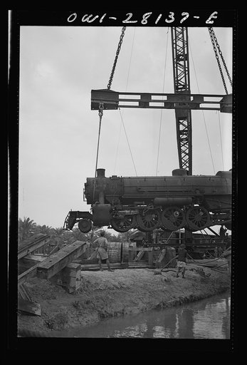 An American locomotive being unloaded from a lighter somewhere in the Middle East. This engine will be used in the hauling of supplies for the aid of Russia
