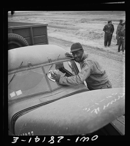 Somewhere on the Persian corridor with a United States Army truck convoy carrying supplies for the aid of Russia. The driver cleaning the desert dust off his windshield
