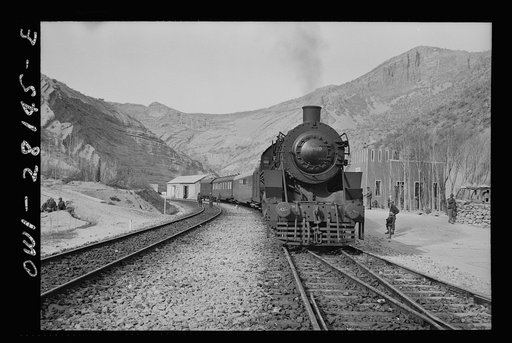 Somewhere in Iran. An American engine transporting allied aid for Russia, stopping at a station rimmed by mountains