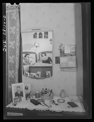 Untitled photo, possibly related to: Niagara Falls, New York. Elaine Colgan's bureau in Mrs. Hannegan's boardinghouse. In the mirror she can be seen reading a letter from home to her roommate, Alice. Girls live two and three in a room; pay eight dollars a week board. Receiving and writing letters is