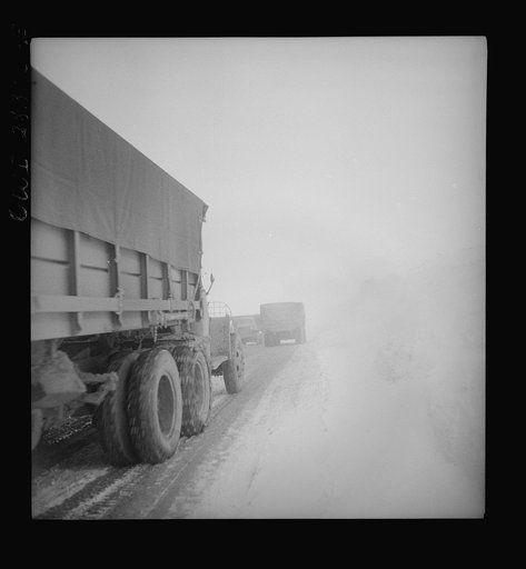 Somewhere in the Persian corridor. United States Army trucks carrying supplies for the aid of Russia. American truck convoy in one-way snowbound mountain pass must get by this disabled truck which is risky on a slippery climb