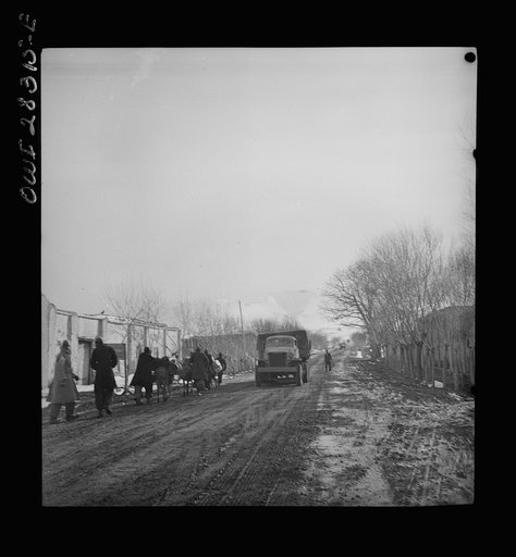 Somewhere in the Persian corridor. A United States Army truck convoy carrying supplies for the aid of Russia. The convoy passing through a Persian village