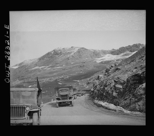 Somewhere in the Persian corridor. A United States Army truck convoy carrying supplies for the aid of Russia. Part of the convoy pulling up a mountain road. The convoy leader in a jeep at the left