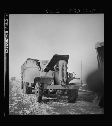 Somewhere in the Persian corridor. A United States truck convoy carrying supplies for aid to Russia. The driver is checking the oil