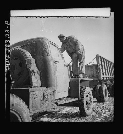 Somewhere in the Persian corridor. A United States truck convoy carrying supplies for the aid of Russia. The driver is cleaning the mud from his windshield
