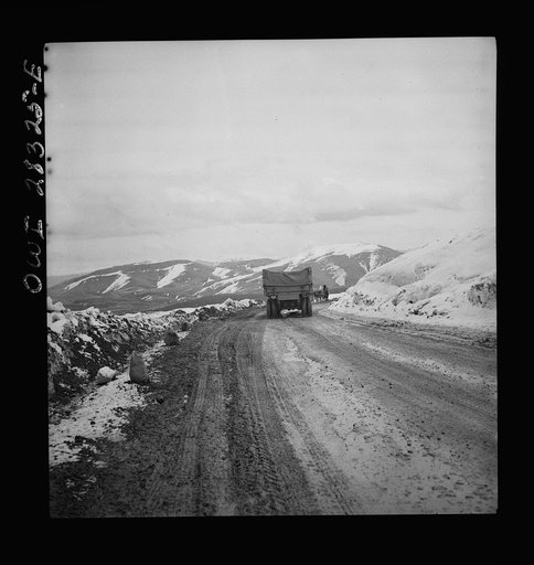 Somewhere in the Persian corridor. A United States Army truck convoy carrying supplies for the aid of Russia. A truck near the top of the snow-covered mountain making the difficult climb. An Iranian native is leading his livestock on the road