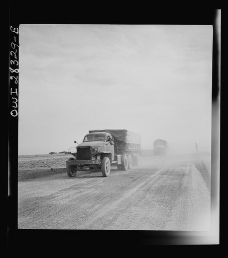Somewhere in the Persian corridor. A United States truck convoy carrying supplies for the aid of Russia. Trucks are kicking up the dust on the desert road