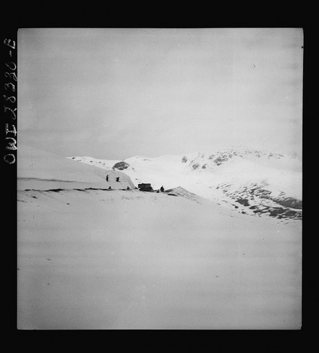 Somewhere in the Persian corridor. A United States Army truck convoy carrying supplies for Russia. Trucks are rounding a mountain peak. Iranian workmen who keep the road open are standing aside as the trucks move through the snow-covered pass