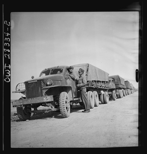Somewhere in the Persian corridor. A United States Army truck convoy carrying supplies for the aid of Russia. The convoy is about to start as the leader checks with the first driver