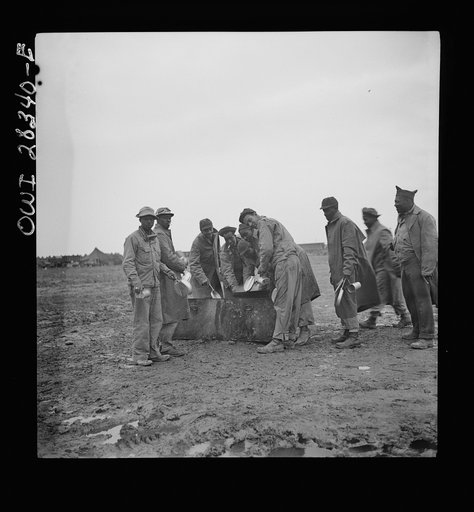 Somewhere in the Persian corridor. A United States Army truck convoy carrying supplies for Russia. Colored American soldier truck drivers washing their mess kits, having just finished a hard day's driving in the rain over mud roads