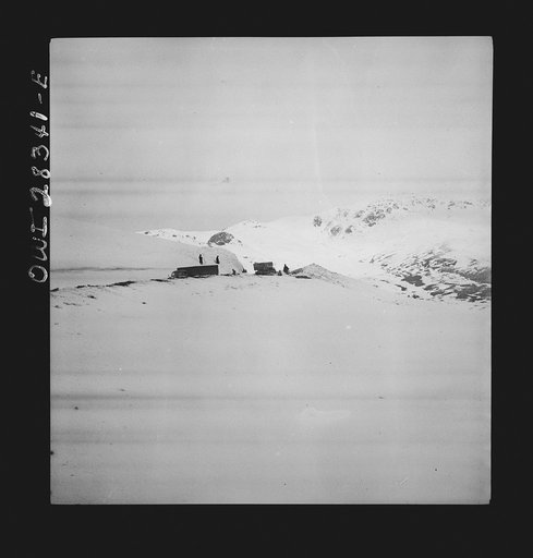 Somewhere in the Persian corridor. A United States Army truck convoy carrying supplies for Russia rounding a difficult turn on the snow-covered pass at the top of a mountain. Iranian workmen who keep the road open are standing aside to allow the trucks to move on