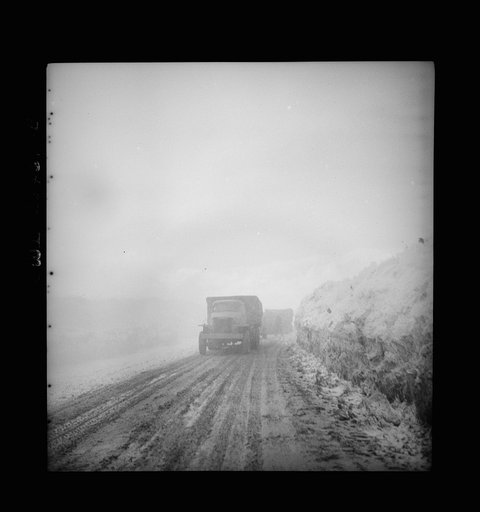 Somewhere in the Persian corridor. A United States Army truck convoy carrying supplies for Russia climbing into the clouds through a risky pass over the mountains. The road was cut out of the ice