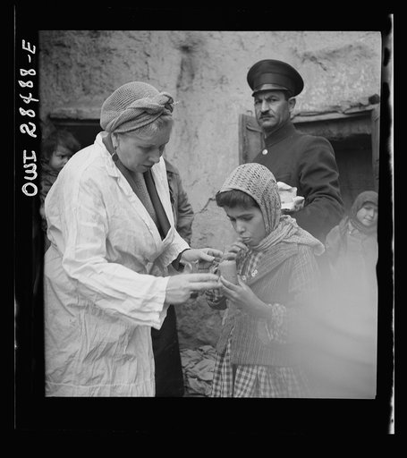 Teheran, Iran. Mrs. Louis Dreyfus, wife of the United States Minister to Iran, giving food to native children