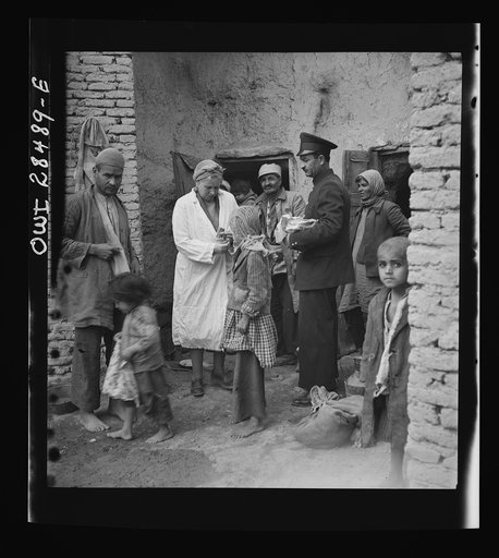 Teheran, Iran. Mrs. Louis Dreyfus, wife of the United States Minister to Iran, giving food to native children