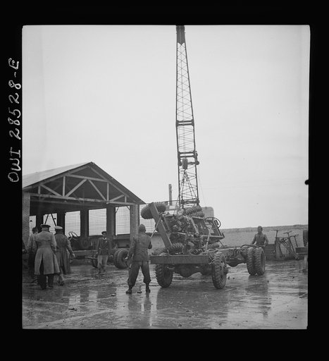 A derrick moving a chassis as the men work ankle deep in water at an American truck assembly plant somewhere in Iran