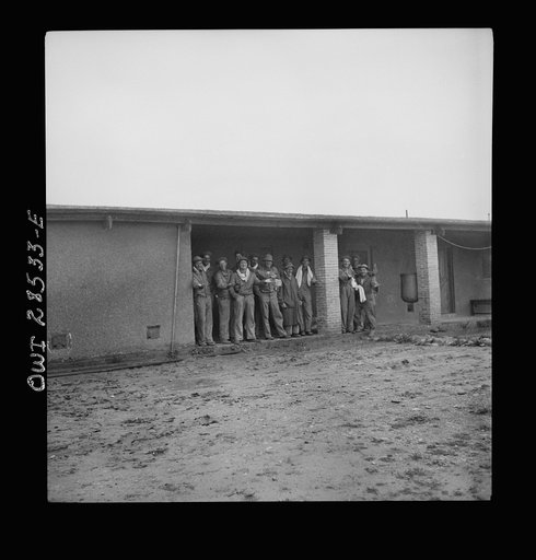 American troops waiting for the rain to stop so that they can get washed at chow time. These boys work at an assembly plant putting trucks together for Russia. Somewhere in Iran