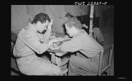 Lieutenant Robert Byrnes, twenty-six, Saint Louis, Missouri, who now has three ME-109 emeny fighter planes to his credit, is shown here with Major Glade B. Bilby of Skidmore, Missouri, as the pass some time with a checker game. Major Bilby is commanding officer of Sixty-Fourth fighter squadron of th