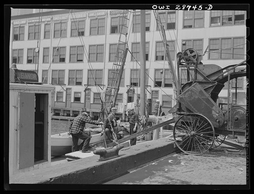 New York, New York. Motor-driven ice machine pouring crushed ice into the hold of a Gloucester fishing boat. This ice is used to store freshly-caught fish during the trip