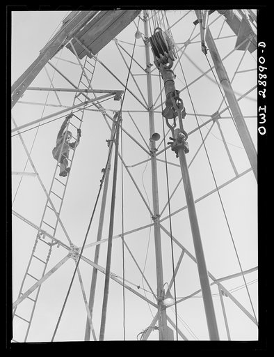 Freeport Sulphur Company, Hoskins Mound, Texas. A derrick man climbing up a sulphur well derrick as a pipe is about to be pulled