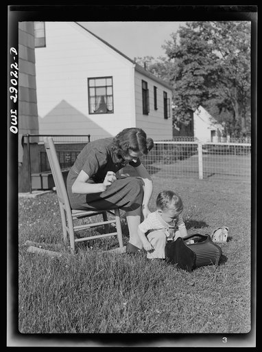 Untitled photo, possibly related to: A mother sewing a button on her child's overalls. Silver Spring, Maryland