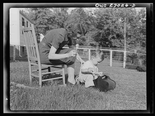 Untitled photo, possibly related to: A mother sewing a button on her child's overalls. Silver Spring, Maryland