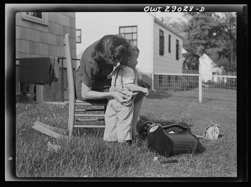 Untitled photo, possibly related to: A mother sewing a button on her child's overalls. Silver Spring, Maryland