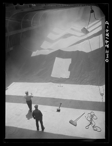 Buffalo, New York. Inside the half-empty hold of a grain boat from Deluth which is unfolding wheat at a grain elevator on the Erie Canal. In the extreme background the "leg" draws wheat into the tower by means of an endless belt of buckets. A shovel rigged up on ropes scoops the grain into an area w