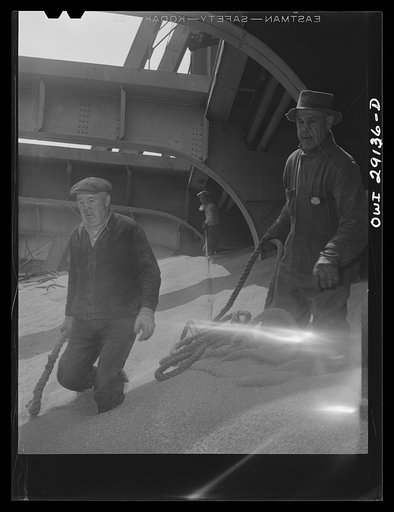Untitled photo, possibly related to: Buffalo, New York. Looking down in the half-empty hatch of a grain boat from Duluth, unloading wheat in a grain elevator on the Erie Canal. Ropes guide the shovel which scoops grain into an area where the "leg" can draw it into a tower by means of an endless belt