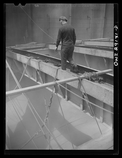Buffalo, New York. Looking down in the half-empty hatch of a grain boat from Duluth, unloading wheat in a grain elevator on the Erie Canal. Ropes guide the shovel which scoops grain into an area where the "leg" can draw it into a tower by means of an endless belt of buckets