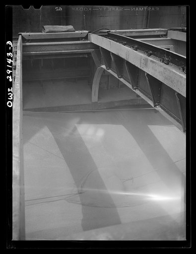 Untitled photo, possibly related to: Buffalo, New York. Looking down in the half-empty hatch of a grain boat from Duluth, unloading wheat in a grain elevator on the Erie Canal. Ropes guide the shovel which scoops grain into an area where the "leg" can draw it into a tower by means of an endless belt