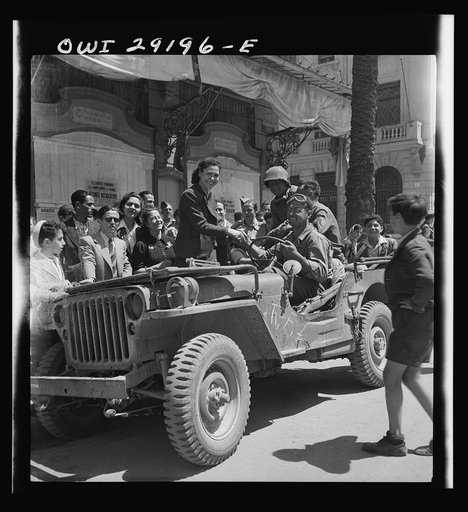 Girls climb on the Jeeps to greet American invading troops in the streets of Tunis