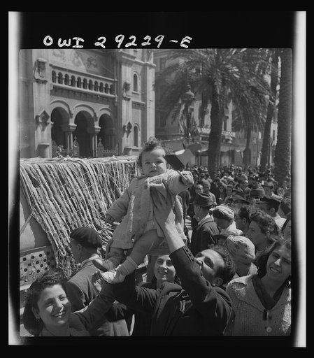French citizens, in a frenzy of excitement, wave tricolors as Allied armies march into Tunis