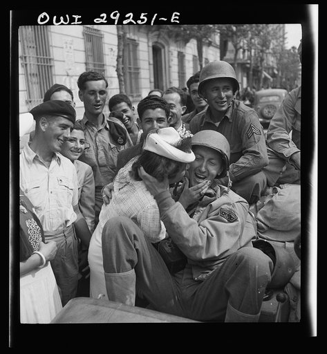 An American correspondent in an Army Jeep is welcomed with a kiss by a young lady in Porto Farina after the Allies frustrated the German evacuation attempts