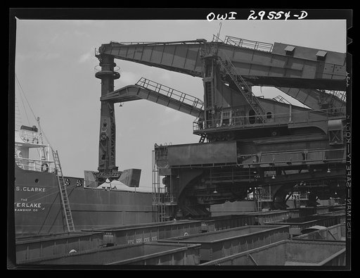 Cleveland, Ohio. Unloading a lake freighter at the Pennsylvania Railroad iron ore docks by means of Hewlett [i.e., Hulett] unloaders. In the foreground, empty cars are waiting to pass under the unloaders to pick up their loads