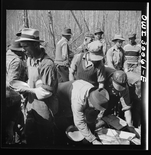 Untitled photo, possibly related to: Spring pulpwood drive on the Brown Company timber holdings in Maine. Woodsmen serve themselves plenty of beans at mid-morning lunch near where they are working. One is planning to eat three thick slices of bread at least six inches square baked by the camp cook