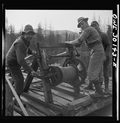 Untitled photo, possibly related to: Spring pulpwood drive on the Brown Company timber holdings in Maine. Woodsmen winching up the boom on Long Pond; during the night the wind has blown the logs in the boom up pond away from the dam through which they must be sluiced