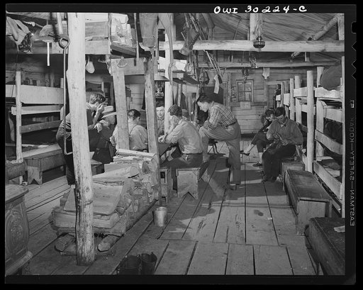 Spring pulpwood drive on the Brown Company timber holdings in Maine. Woodsmen during the evening in the bunkhouse playing cards and greasing their boots before turning in after a thirteen-hour day of driving logs