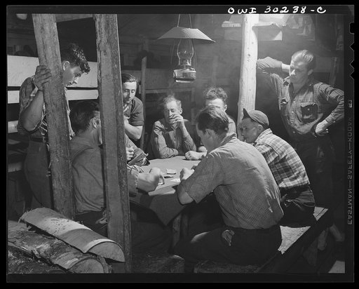 Spring pulpwood drive on the Brown Company timber holdings in Maine. Woodsmen playing cards in the bunkhouse after a thirteen-hour day of driving logs. They are using Canadian money