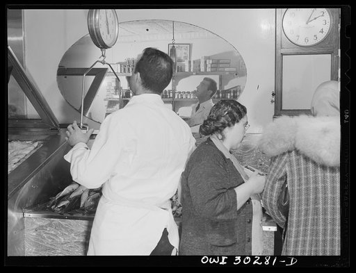 New York, New York. Interior of the DeMartino seafood market where Mrs. DeMartino is selling fish to a customer and her son Joseph weighs up mackerel purchased at the Fulton fish market