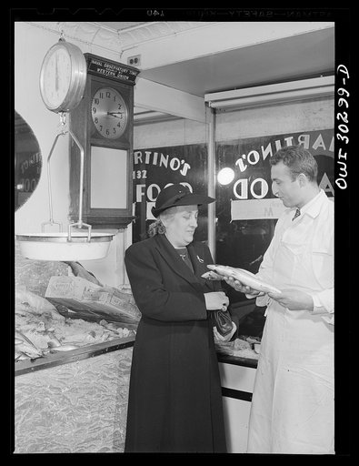 New York, New York. Mrs. Rose Carrendeno buying fish from Joseph DeMartino, which he gets from the Fulton fish market in the morning before starting his day in the store
