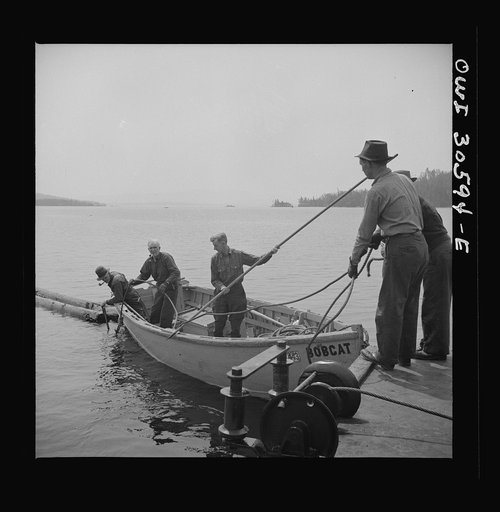 Spring pulpwood drive on the Brown Company timber holdings in Maine. The lake steamer's motor boat casts off to anchor the safety boom on shore while the steamer goes to pick up the full boom